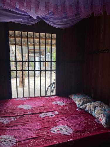 a bedroom with a pink bed with a window at Homestay Nature in Na Hang