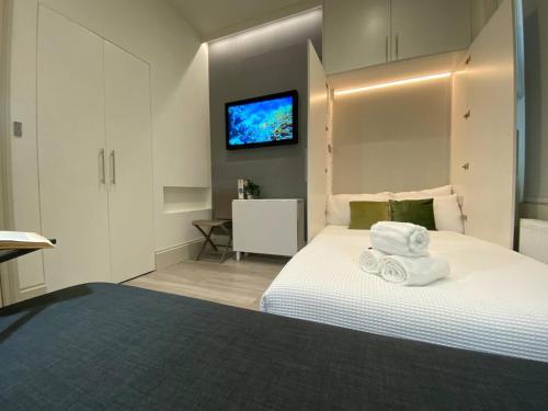 a bedroom with a white bed with a tv on the wall at Apt 03 Beachside Beauty Central Studio Steps from Cafes in Brighton & Hove