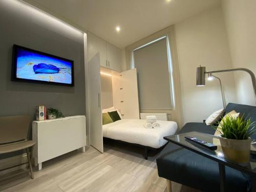 a hotel room with a bed and a tv on the wall at Apt 03 Beachside Beauty Central Studio Steps from Cafes in Brighton & Hove