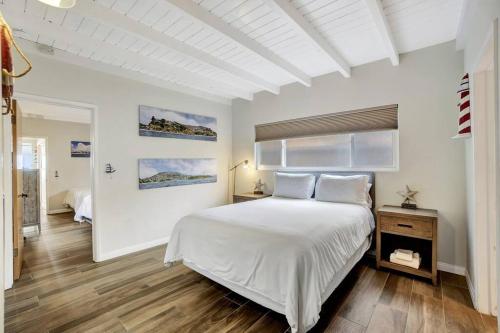 a white bedroom with a large bed and a window at ON THE SAND!! Private Beach! OCEAN FRONT HOT TUB!! in Dana Point