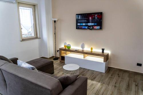ein Wohnzimmer mit einer Couch und einem Fernseher an der Wand in der Unterkunft Gardenie Home: delizioso villino vista mare in Messina