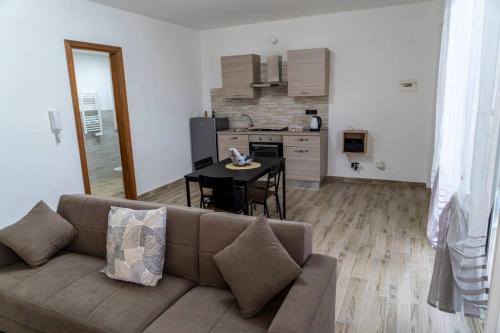 ein Wohnzimmer mit Couch und Tisch und eine Küche in der Unterkunft Gardenie Home: delizioso villino vista mare in Messina