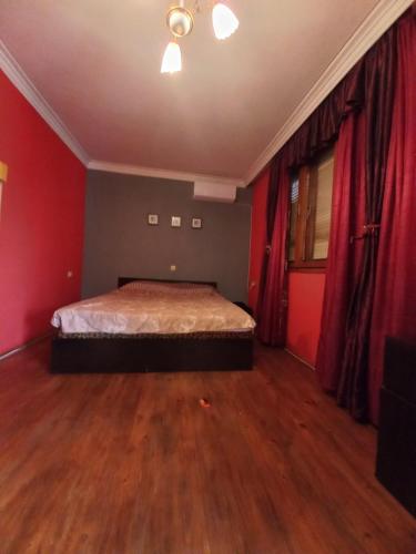 Schlafzimmer mit einem Bett mit roten Wänden und Holzböden in der Unterkunft Къща в село Катунци in Sandanski