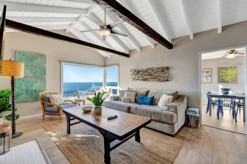 a living room with a couch and a table at OCEAN FRONT Beach HOUSE! Private Stairs to SAND! in Laguna Beach
