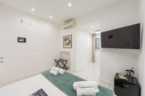 a white living room with a television and two white towels at Maison Morghen in Naples