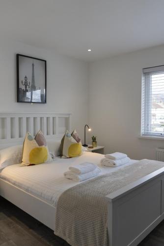 a white bedroom with a large bed with yellow pillows at Hope Apartments Belfast - Tullymore in Belfast