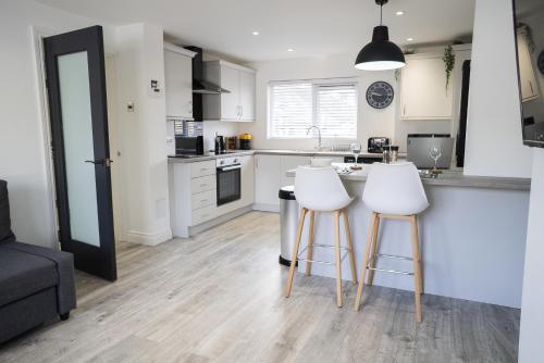 a kitchen with two white bar stools in a kitchen at Hope Apartments Belfast - Tullymore in Belfast