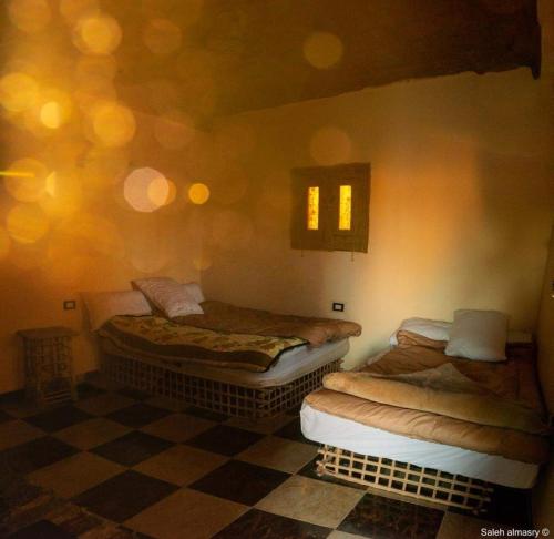 2 łóżka pojedyncze w pokoju z podłogą wyłożoną szachownicą w obiekcie غزاله كامب w mieście Siwa