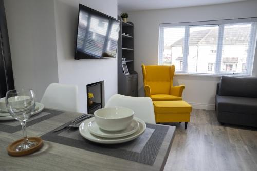 a dining room with a table and a yellow chair at Hope Apartments Belfast - Tullymore in Belfast
