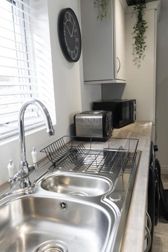 a kitchen with a sink and a clock on the wall at Hope Apartments Belfast - Tullymore in Belfast