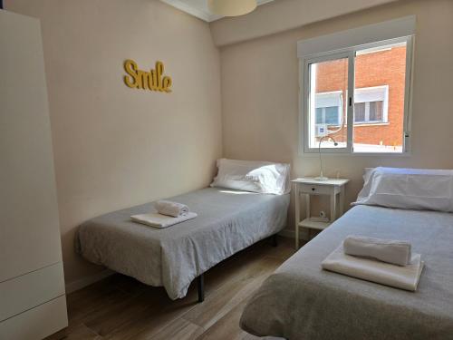 - une petite chambre avec 2 lits et une fenêtre dans l'établissement PASARELA ALMOZARA HOME, à Saragosse