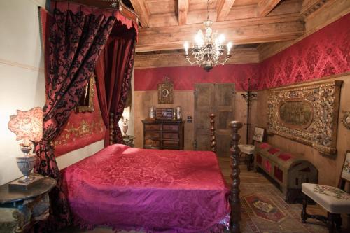 a bedroom with a red bed and a chandelier at B&b di Charme Palazzo Lambertenghi in Tirano