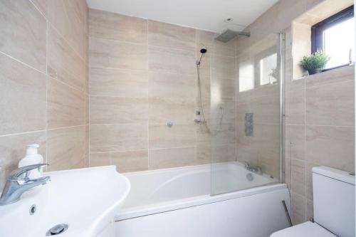 4 Bedroom House 2 baths Dagenham في سوفيريتو: حمام مع حوض ومغسلة ومرحاض