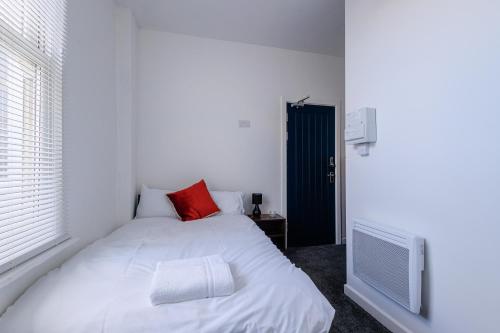 Un dormitorio con una cama blanca con una almohada roja. en Stockton Lodge, en Hartlepool