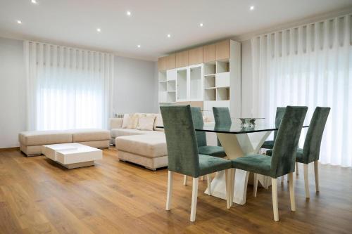 a living room with a glass table and green chairs at Casa D’Adélia in Nazaré