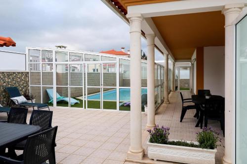 a patio with tables and chairs and a swimming pool at Casa D’Adélia in Nazaré