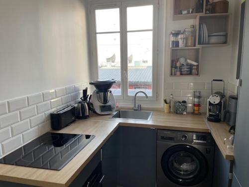 une cuisine avec un évier et une machine à laver dans l'établissement Cosi Appartement, à Clichy