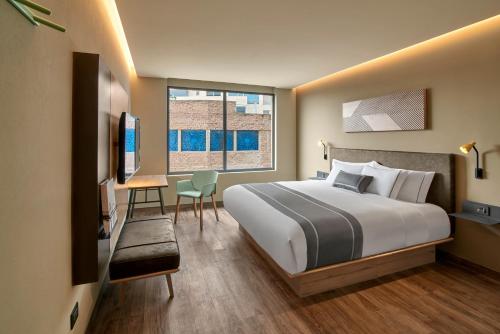 a hotel room with a bed and a desk and a window at City Express Plus by Marriott San Luis Potosi in San Luis Potosí