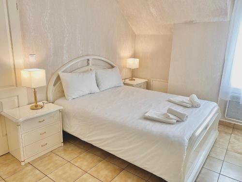 um quarto com uma cama branca com duas toalhas em Villa Briconico em Gonesse