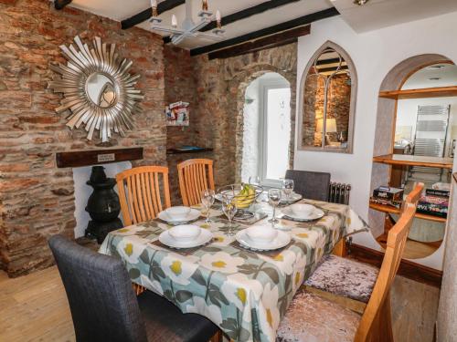 a dining room with a table and chairs and a brick wall at Pebble Bay in Brixham