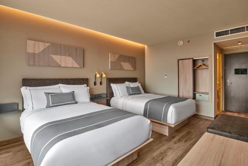 a hotel room with two beds and a hallway at City Express Plus by Marriott San Luis Potosi in San Luis Potosí