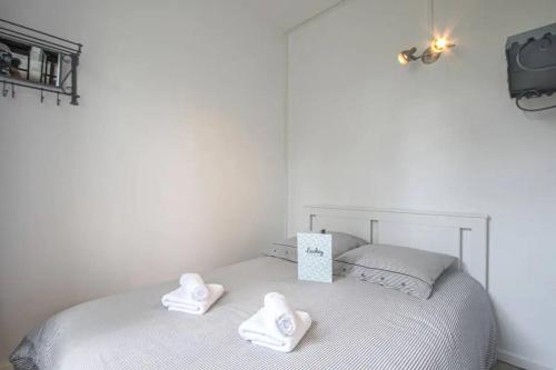 un letto bianco con due asciugamani sopra di Magnifique f2 en plein centre a Cabourg