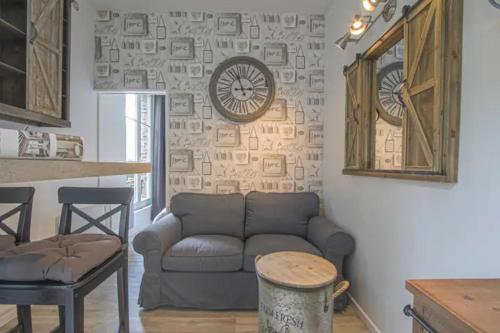 un salon avec un canapé et une horloge au mur dans l'établissement Magnifique f2 en plein centre, à Cabourg