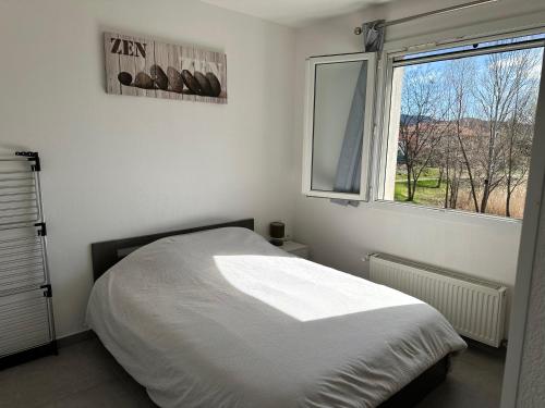 a white bedroom with a bed and a window at Bienvenue chez Sophie & Thomas in Gap
