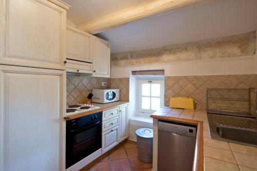 a kitchen with white cabinets and a stove top oven at Le Capitaine in Bonnieux