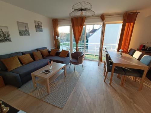 uma sala de estar com um sofá azul e uma mesa em Les vergers de Serris, 6 personnes, 2 PK privés, balcon, lit bébé em Serris