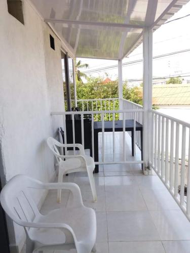 a porch with two white chairs and a table at apartamento vacacional san andes islas JLV in San Andrés