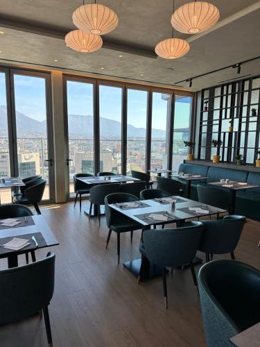 a restaurant with tables and chairs and large windows at Sky Hotel Tirana in Tirana