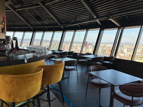 a bar with chairs and tables in a room with windows at Sky Hotel Tirana in Tirana