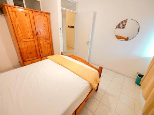 a bedroom with a bed and a wooden cabinet at Fibonacci Beachfront Apartment in Flic-en-Flac