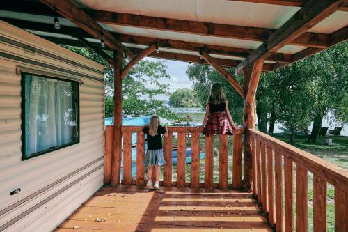 two girls standing on the porch of a cabin at Holender Przy Plaży in Wilimy