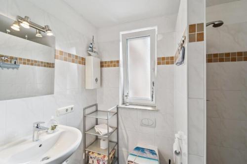 een witte badkamer met een wastafel en een spiegel bij Ferienwohnung in Ottersberg mit Eigener Terrasse in Ottersberg