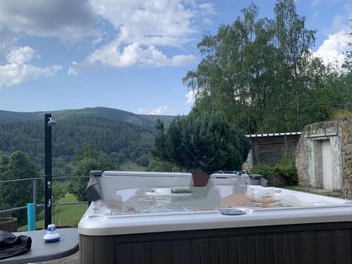 Majestic Holiday Home with Jacuzzi في Unterschönau: وجود حوض استحمام جالس فوق شرفة مطلة