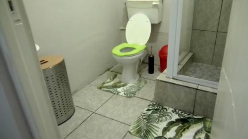 a bathroom with a toilet with a green seat at Vee’s Guest House in East London