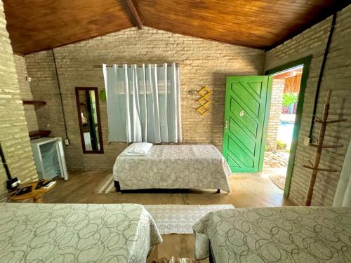 a bedroom with two beds and a green door at Pousada Flor De Jambú in São Miguel do Gostoso