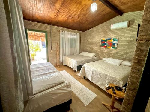 1 dormitorio con 2 camas y ventana en Pousada Flor De Jambú, en São Miguel do Gostoso