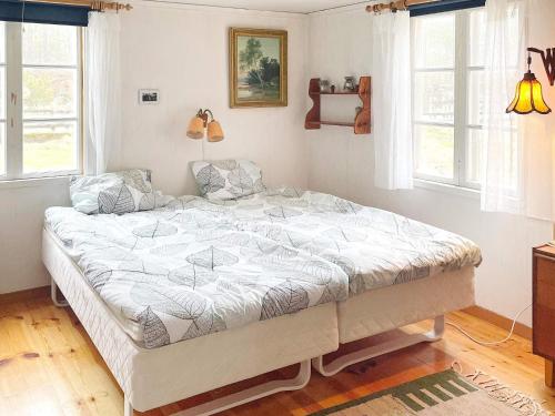 a bedroom with a large bed in a room with windows at Idyllic Getaway with Private Beach in Abbetorp