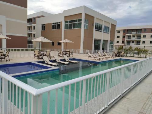 einen Pool mit Stühlen und Tischen sowie ein Gebäude in der Unterkunft La Palma 204 - Apartamento na Praia dos Milionários - Ilhéus/BA in Ilhéus