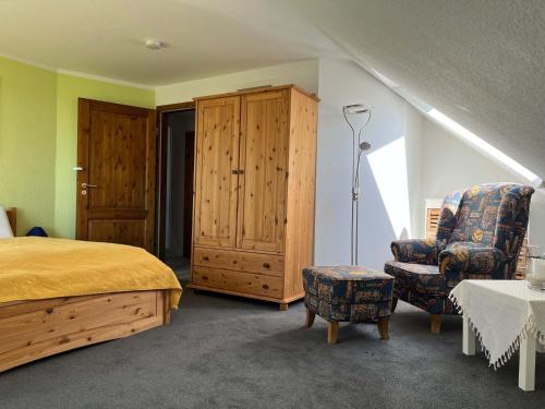 een slaapkamer met een bed, een stoel en een kast bij Ferienwohnung Weitblick auf der Sonneninsel Fehmarn in Schlagsdorf