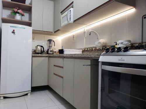 uma cozinha com armários brancos e um forno com placa de fogão em Ap 1 quarto Mobiliado em Gravataí