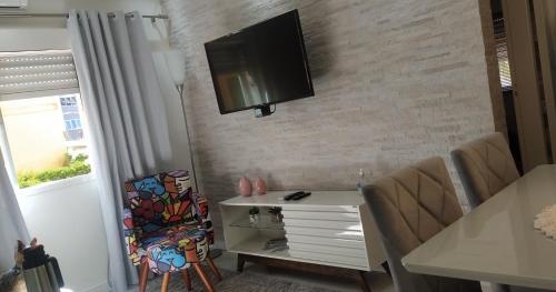 uma sala de estar com uma televisão pendurada numa parede de tijolos em Ap 1 quarto Mobiliado em Gravataí