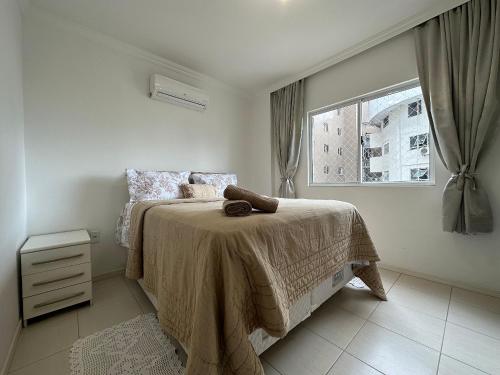een witte slaapkamer met een bed en een raam bij BC01- Suíte+1 | Centro | Churrasqueira | Garagem in Balneário Camboriú