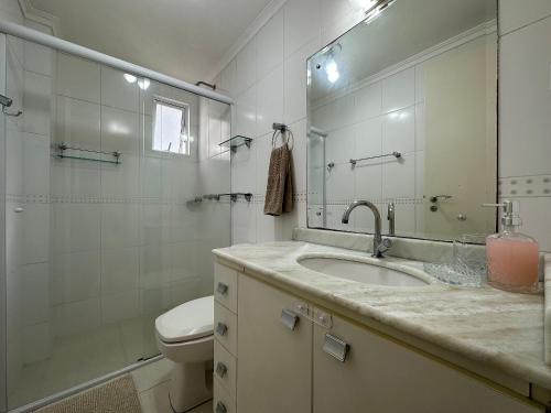 een badkamer met een wastafel, een toilet en een spiegel bij BC01- Suíte+1 | Centro | Churrasqueira | Garagem in Balneário Camboriú