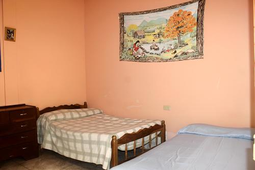 a bedroom with two beds and a painting on the wall at Hostal Delmy in Suchitoto