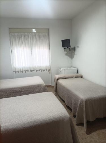 Cette chambre comprend 2 lits et une télévision. dans l'établissement PENSIÓN CARLOS III, à Tomelloso