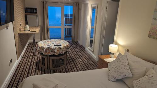 a bedroom with a bed and a table with a view at Ivybridge Guesthouse in Fishguard